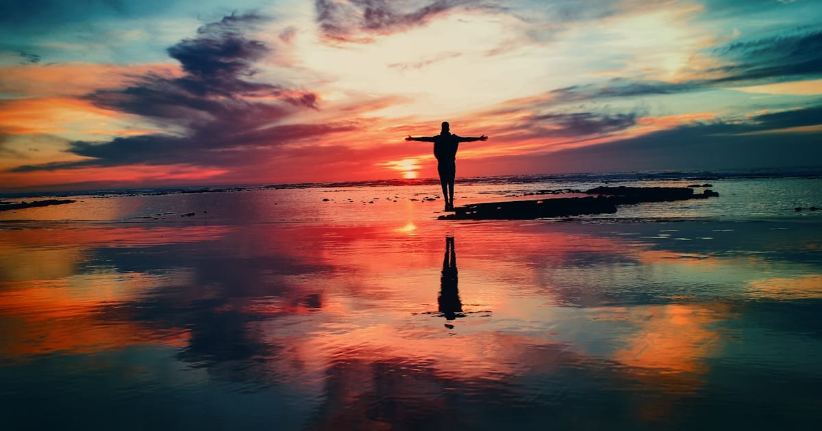Person silhouetted at sunset on reflective water