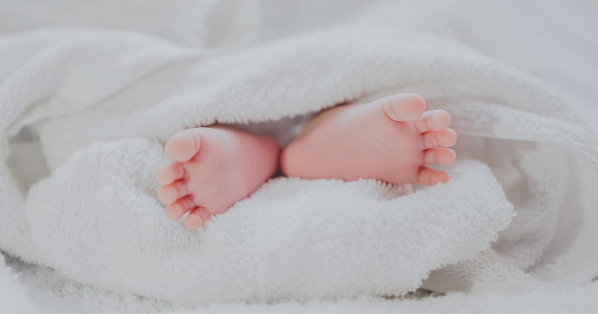 Newborn baby feet wrapped in white blanket