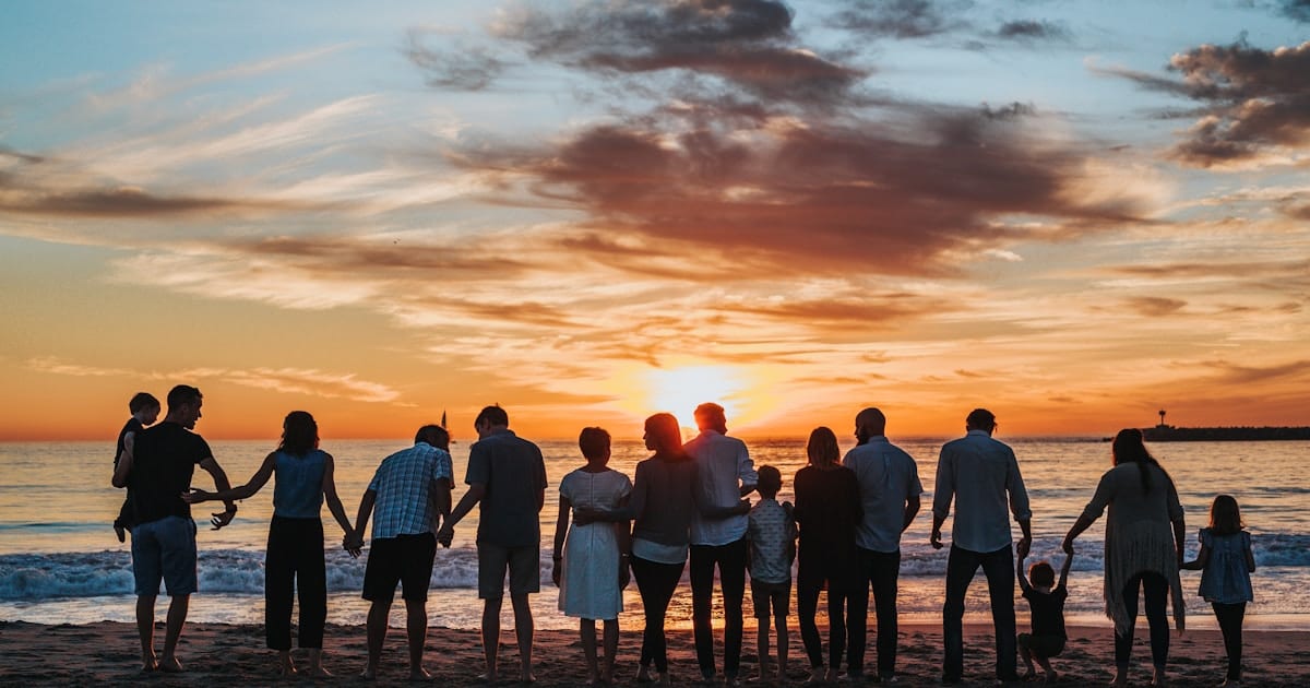 Group of people arm-in-arm at beach sunset