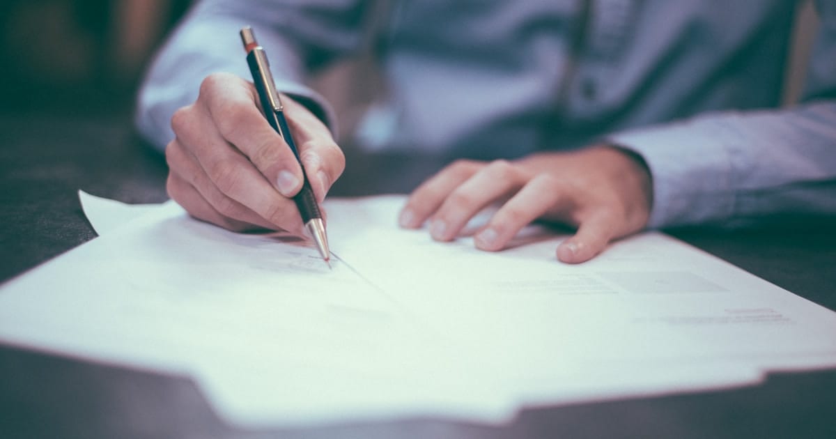 Person signing official documents at desk