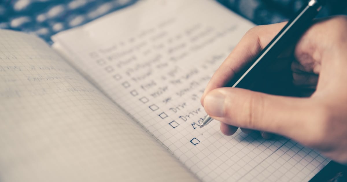 Person writing a checklist on paper